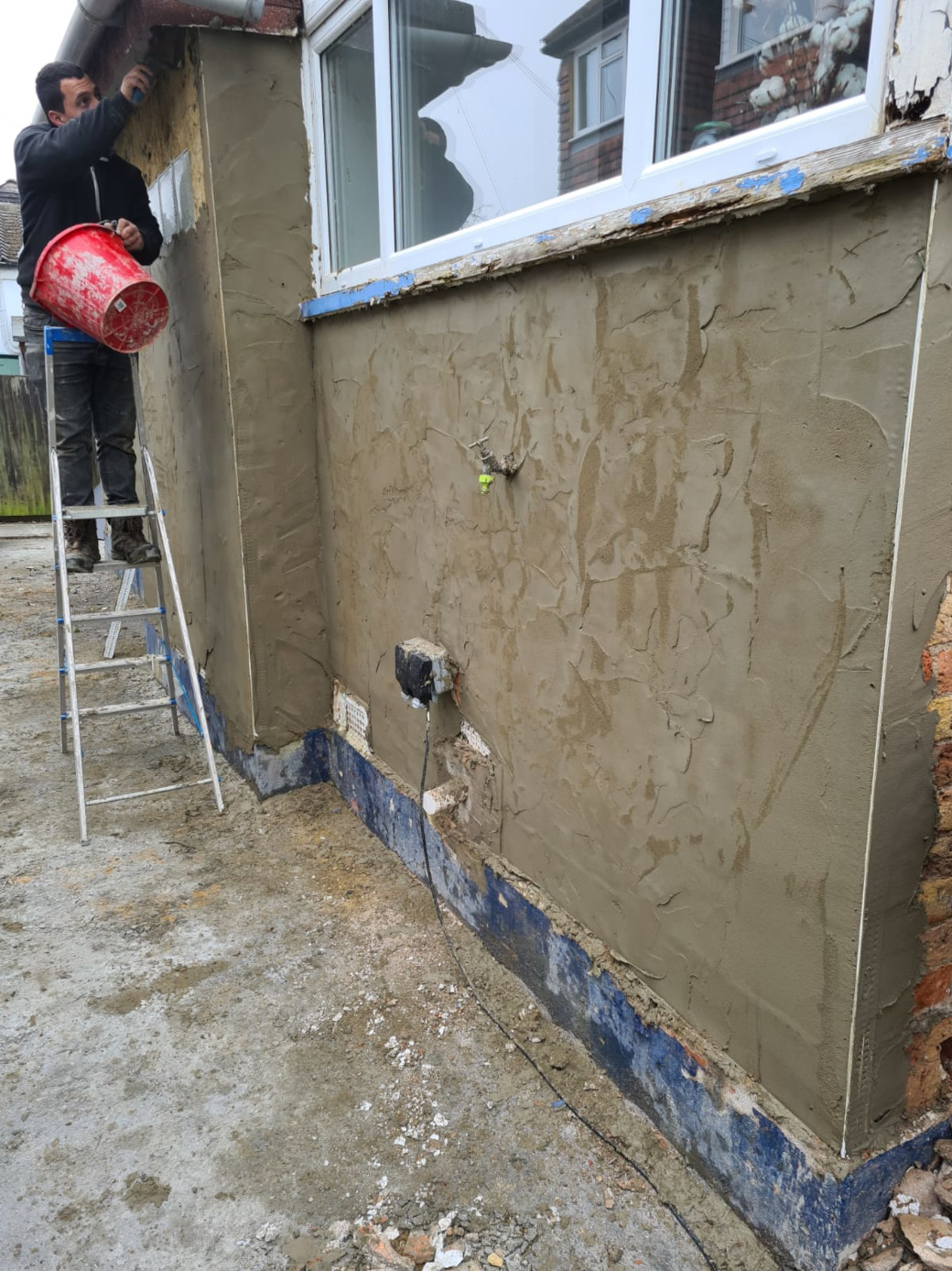 Apply base layer of waterproof render to brickwork.